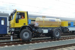 Beide zweirädrige Schienenfahrgestelle werden hinter den Straßenachsen installiert. Das Fahrzeug ist mit CCTV Kamerasystem für Rückwärtsfahrt als auch mit Eisenbahnbeleuchtung und Beleuchtung zur Nachtarbeit ausgestattet. Alle Arbeitsbewegungen auf den Schienen wird elektrisch aus der Fahrerkabine oder aus den Seitensteuerpulten gesteuert. Die Reversionsgetriebe ermöglicht Schienenfahrt mit gleicher Geschwindigkeit in beiden Richtungen.